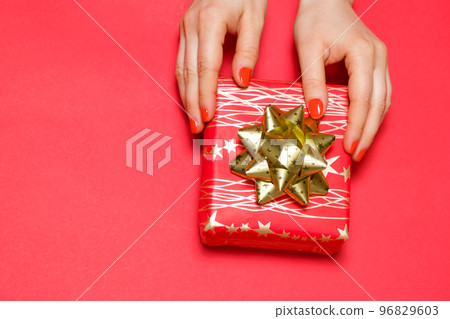 Beautiful red gift box with bow in women's hands, top view, copy space for text. 96829603