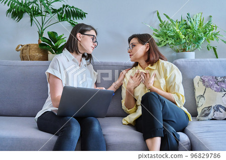 Female psychologist and middle aged woman patient sitting together on couch in office 96829786