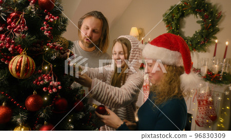 Happy family decorating Christmas tree with toys Happy family decorating Christmas tree with toys 96830309