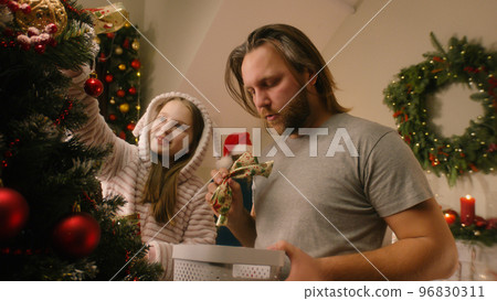 Daughter helps dad to decorate Christmas tree Daughter helps dad to decorate Christmas tree 96830311