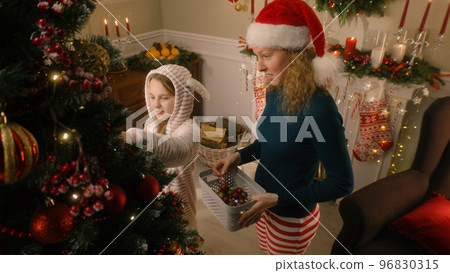 Daughter helps mom to decorate Christmas tree Daughter helps mom to decorate Christmas tree 96830315
