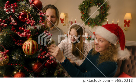 Happy family decorating Christmas tree with toys Happy family decorating Christmas tree with toys 96830318