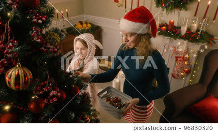 Daughter helps mom to decorate Christmas tree Daughter helps mom to decorate Christmas tree 96830320