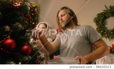 Daughter helps dad to decorate Christmas tree Daughter helps dad to decorate Christmas tree 96830323