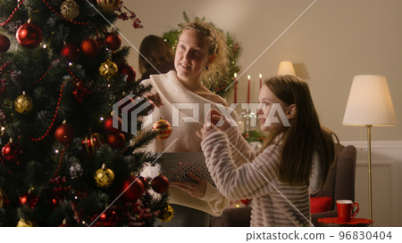 Daughter with mom decorating Christmas tree Daughter with mom decorating Christmas tree 96830404