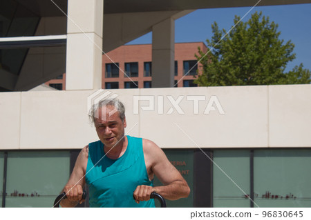 mature man training his body on the street with sports machines mature man training his body on the street with sports machines 96830645