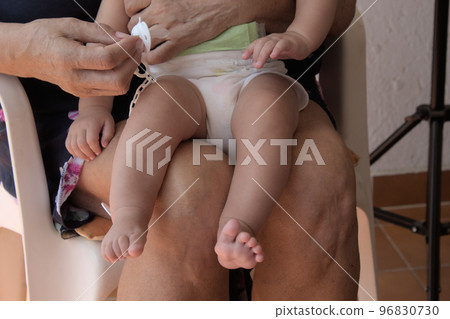 close-up of grandmother holding her lovely newborn grandson on her lap close-up of grandmother holding her lovely newborn grandson on her lap 96830730