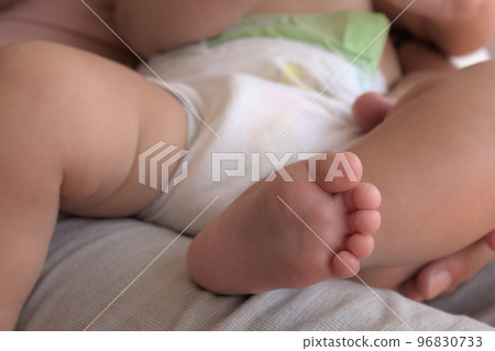 close-up of a foot of a baby on a lap of his father close-up of a foot of a baby on a lap of his father 96830733