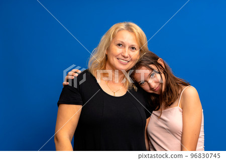 Headshot portrait of a smiling multiracial family of different female generations. Happy Caucasian mother in her 40s hugging the shoulders of a pretty Hispanic teenage daughter Headshot portrait of a smiling multiracial family of different female generations. Happy Caucasian mother in her 40s hugging the shoulders of a pretty Hispanic teenage daughter 96830745