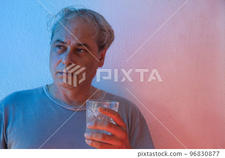 portrait with copy space of mature man with ambient color light on white background having drink 96830877