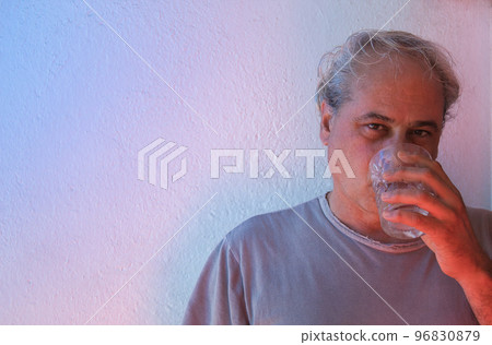 portrait with copy space of mature man with red and blue ambient color lights on white background having drink 96830879
