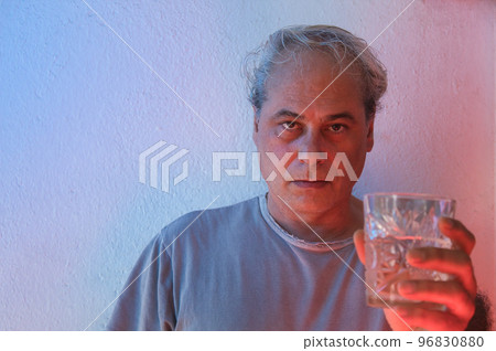 portrait with copy space of mature man with ambient color lights on white background showing a cold drink portrait with copy space of mature man with ambient color lights on white background showing a cold drink 96830880