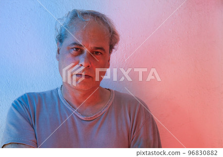 portrait with copy space of mature man with ambient color lights on a white background looking seriously at camera portrait with copy space of mature man with ambient color lights on a white background looking seriously at camera 96830882