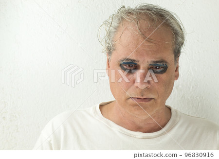 close-up of a mature man with painted eyes on a white background with sad expression close-up of a mature man with painted eyes on a white background with sad expression 96830916