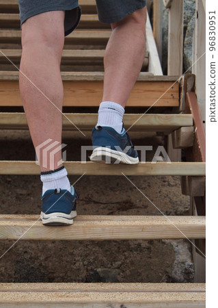 view from behind of the feet of a man climbing a wooden ladder 96830951