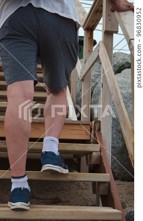 view from behind of the feet of a man climbing a wooden ladder on the beach view from behind of the feet of a man climbing a wooden ladder on the beach 96830952