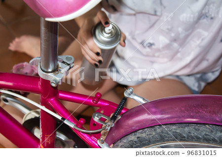 hands of a girl cleaning her bike with a rag and spray at home 96831015