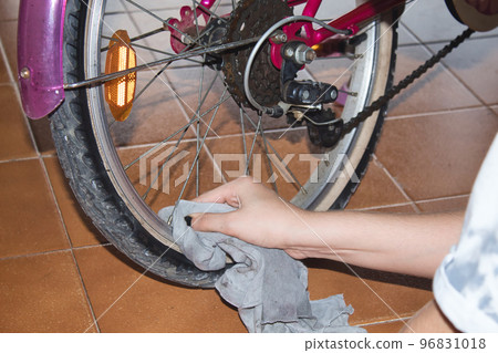 view of a hands of a girl cleaning her bike with a rag and spray at home view of a hands of a girl cleaning her bike with a rag and spray at home 96831018