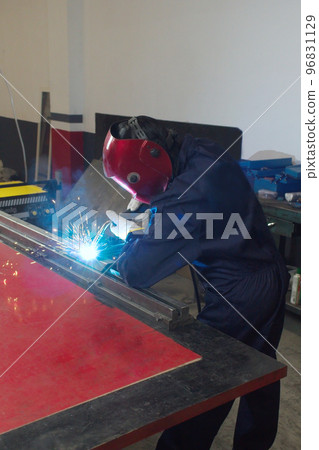 worker woman working in a workshop welding metal with helmet and overalls worker woman working in a workshop welding metal with helmet and overalls 96831129