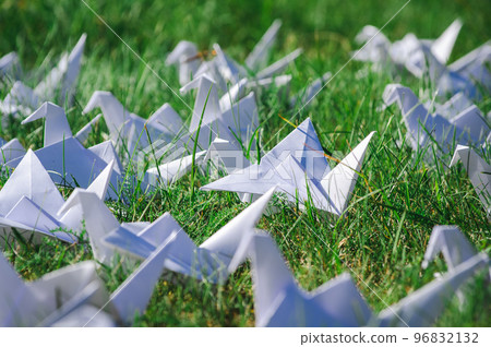 Japanese folded Origami cranes on fresh grass. Hundreds handmade paper birds on green field with copy space. 1000 thousand crane tsuru sculpture topic. Symbol of peace, faith, health, wishes and hope  96832132