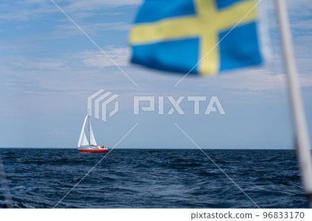 Sailboat on blue open sea with Sweden flag foreground. Concept of travel, adventure and vacation. Sailboat on blue open sea with Sweden flag foreground. Concept of travel, adventure and vacation. 96833170
