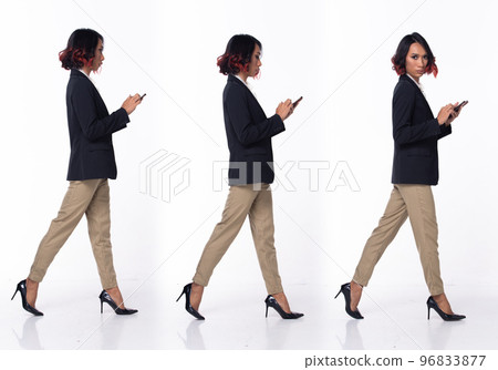 Full length 20s Asian Woman wear formal Business dress blazer high heel shoes. Black short curl hair female walking happy smile hold smart phone, walk forward left right over white background isolated 96833877