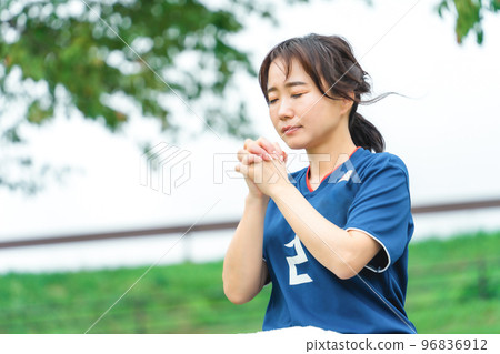 A Japanese woman who is a soccer fan and supporter cheering for the Japan national team as if praying 96836912