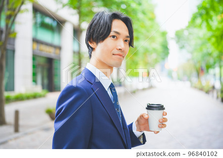 手拿咖啡走在辦公區的商人 手拿咖啡走在辦公區的商人 96840102