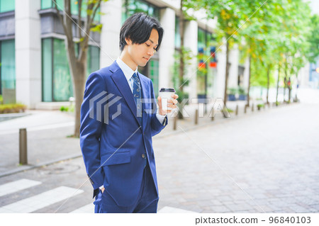 手拿咖啡走在辦公區的商人 手拿咖啡走在辦公區的商人 96840103