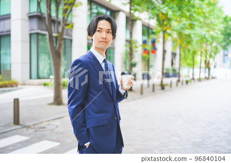 Businessman walking in the office district with coffee in hand 96840104