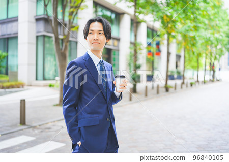 手拿咖啡走在辦公區的商人 手拿咖啡走在辦公區的商人 96840105