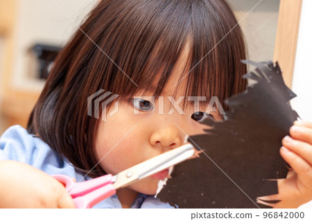 Girl cutting paper with scissors 96842000