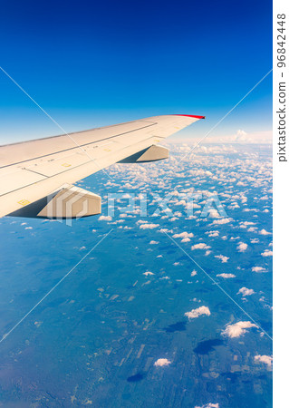 View from the airplane window at a beautiful cloudy sky and the airplane wing View from the airplane window at a beautiful cloudy sky and the airplane wing 96842448
