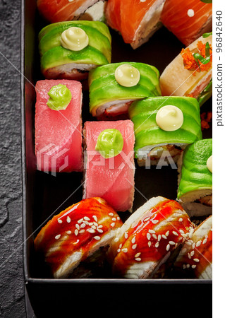 Set of various uramaki with salmon, tuna, eel and avocado in cardboard box 96842640