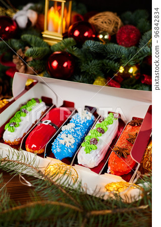 Christmas eclairs with cherry and cream fillings on a background of glowing garlands 96842834