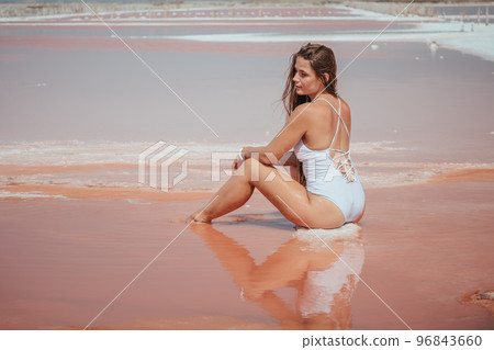 Young woman with long hair in pink salty lake with crystals of salt. Extremely salty pink lake, colored by microalgae with crystalline salt depositions. Spa, beauty and health care concept. Young woman with long hair in pink salty lake with crystals of salt. Extremely salty pink lake, colored by microalgae with crystalline salt depositions. Spa, beauty and health care concept. 96843660