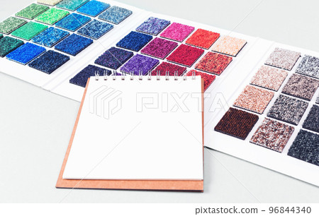 Multicolored carpet swatches catalogue book and notepad on blue desk background. Interior or refurbishment design with copy space. Trendy magenta and blue green Multicolored carpet swatches catalogue book and notepad on blue desk background. Interior or refurbishment design with copy space. Trendy magenta and blue green 96844340