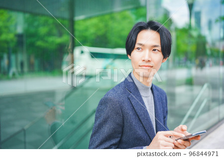A man operating a smartphone in an office district A man operating a smartphone in an office district 96844971