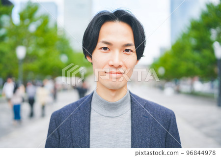 A man wearing a knitwear smiling in an office district A man wearing a knitwear smiling in an office district 96844978