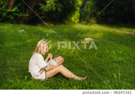 A mother holds a happy baby boy in her arms in a summer park 96845381
