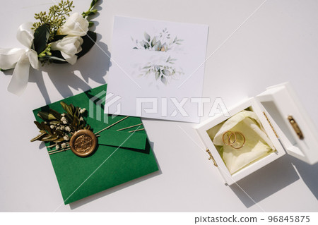 Top view of wedding rings on oaths. A wooden box for wedding rings. Beautiful boutonniere on table Top view of wedding rings on oaths. A wooden box for wedding rings. Beautiful boutonniere on table 96845875