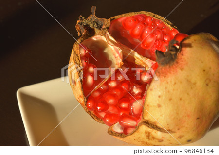 Cracked pomegranate fruit on a plate Cracked pomegranate fruit on a plate 96846134