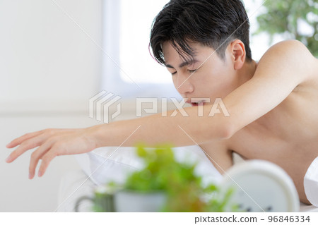 Young man waking up in bed in the morning and trying to turn off the alarm clock 96846334