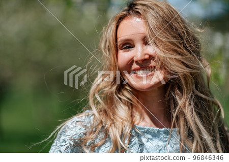Portrait of a blonde in the park. Beautiful woman with long blond hair in a blue dress. Portrait of a blonde in the park. Beautiful woman with long blond hair in a blue dress. 96846346