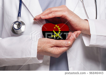 Angolan doctor holding heart with flag of Angola background.  96846443
