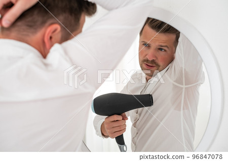 Man with hyperhidrosis sweating very badly under armpit trying to dry with fan Man with hyperhidrosis sweating very badly under armpit trying to dry with fan 96847078
