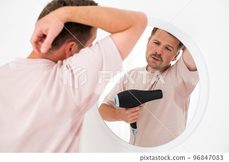 Man with hyperhidrosis sweating very badly under armpit trying to dry with fan Man with hyperhidrosis sweating very badly under armpit trying to dry with fan 96847083