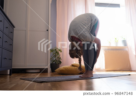 Mature woman doing stretching at home. Uttanasana yoga pose Mature woman doing stretching at home. Uttanasana yoga pose 96847148