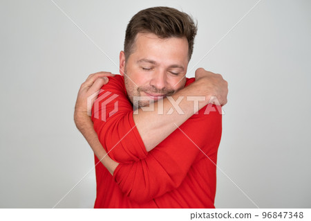 Confident smiling caucasian man holding hugging himself 96847348