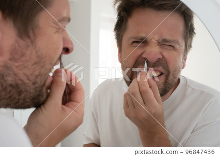 suffering bearded man plucking out his nose hair. 96847436